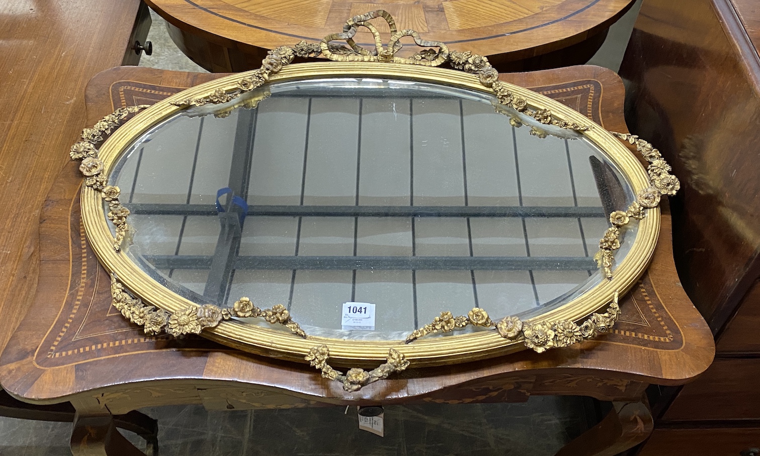 An Edwardian oval giltwood and gesso wall mirror with ribbon and flower swagged border, width 87cm, height 68cm